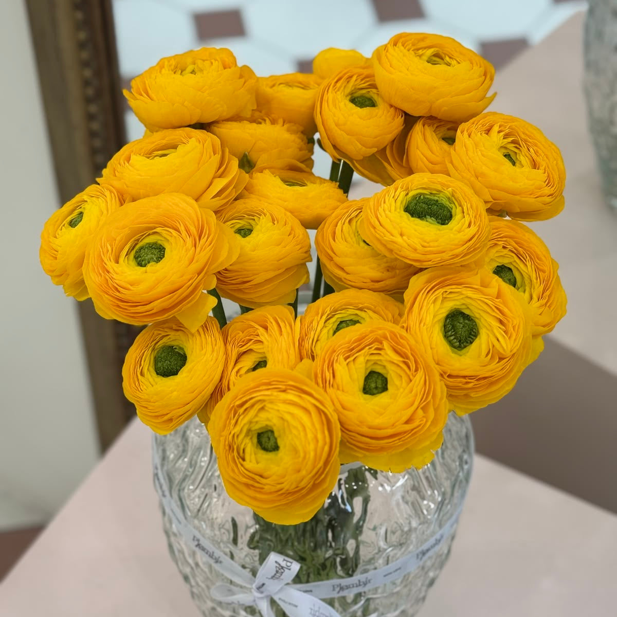 Bouquet of yellow flowers in a clear glass vase on a table.